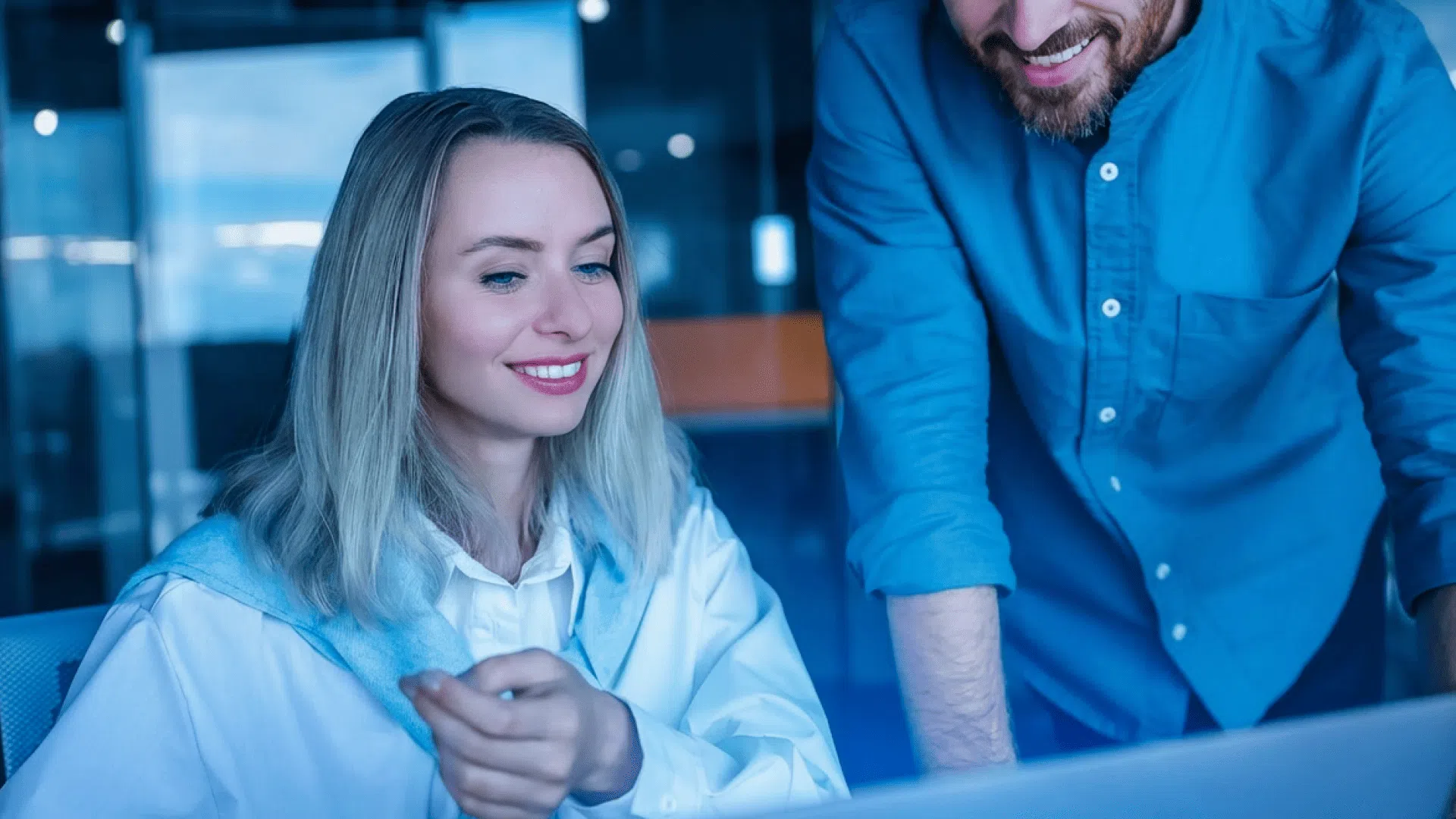 Two people working together on a computer in the office.