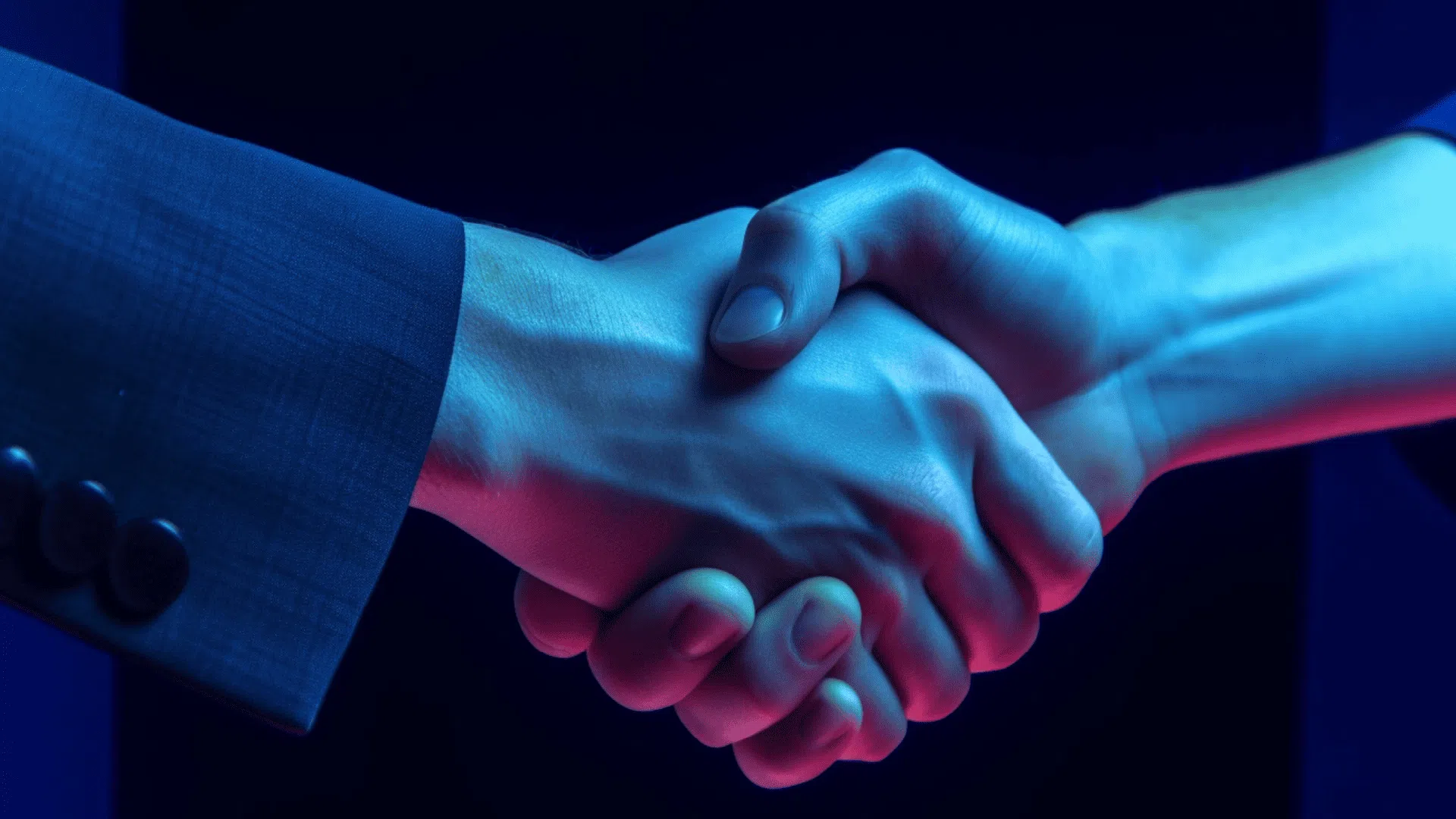 Zwei Personen im Handschlag bei blauer Beleuchtung.