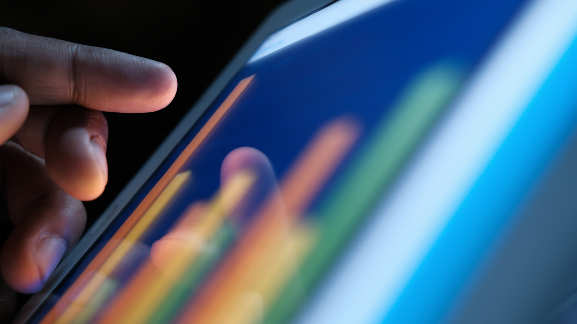 Finger tippt auf Tablet mit buntem Liniendiagramm