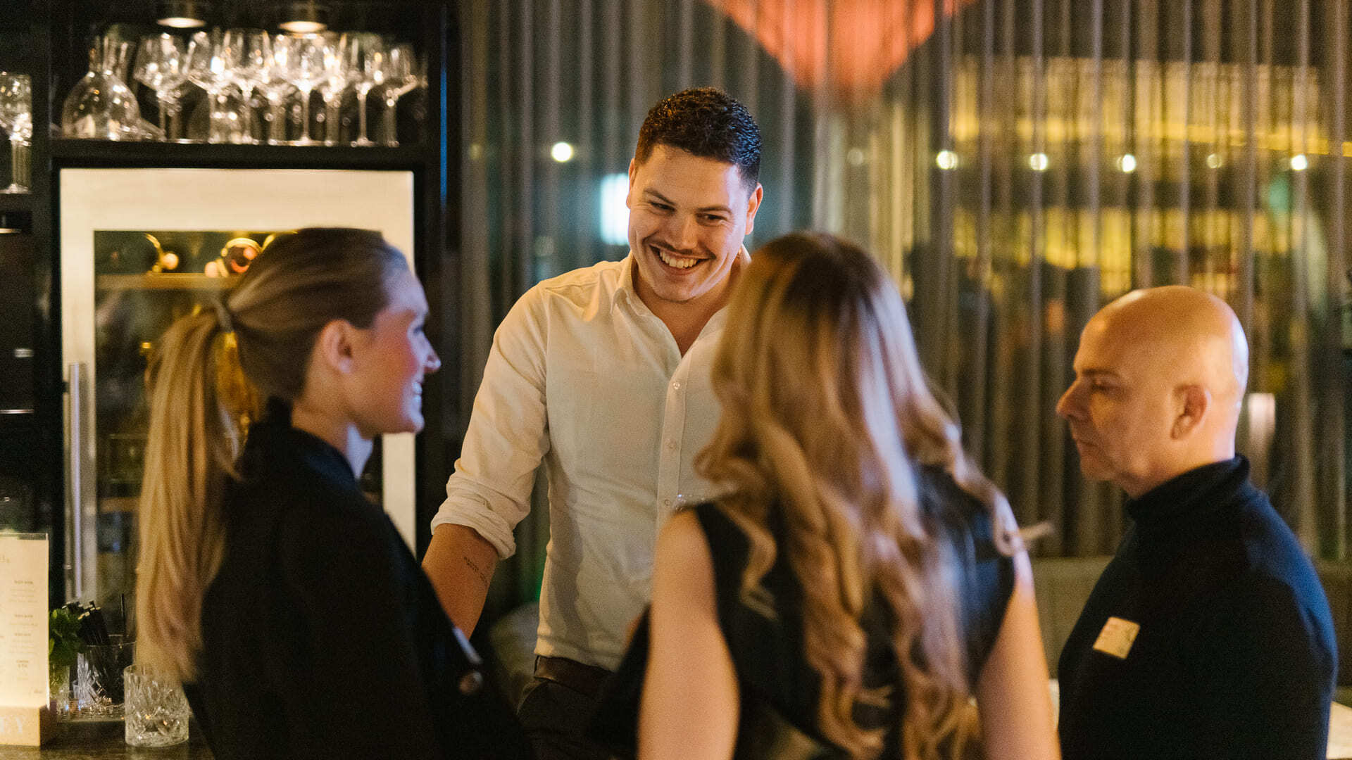 Group of people smiling and talking at a bar