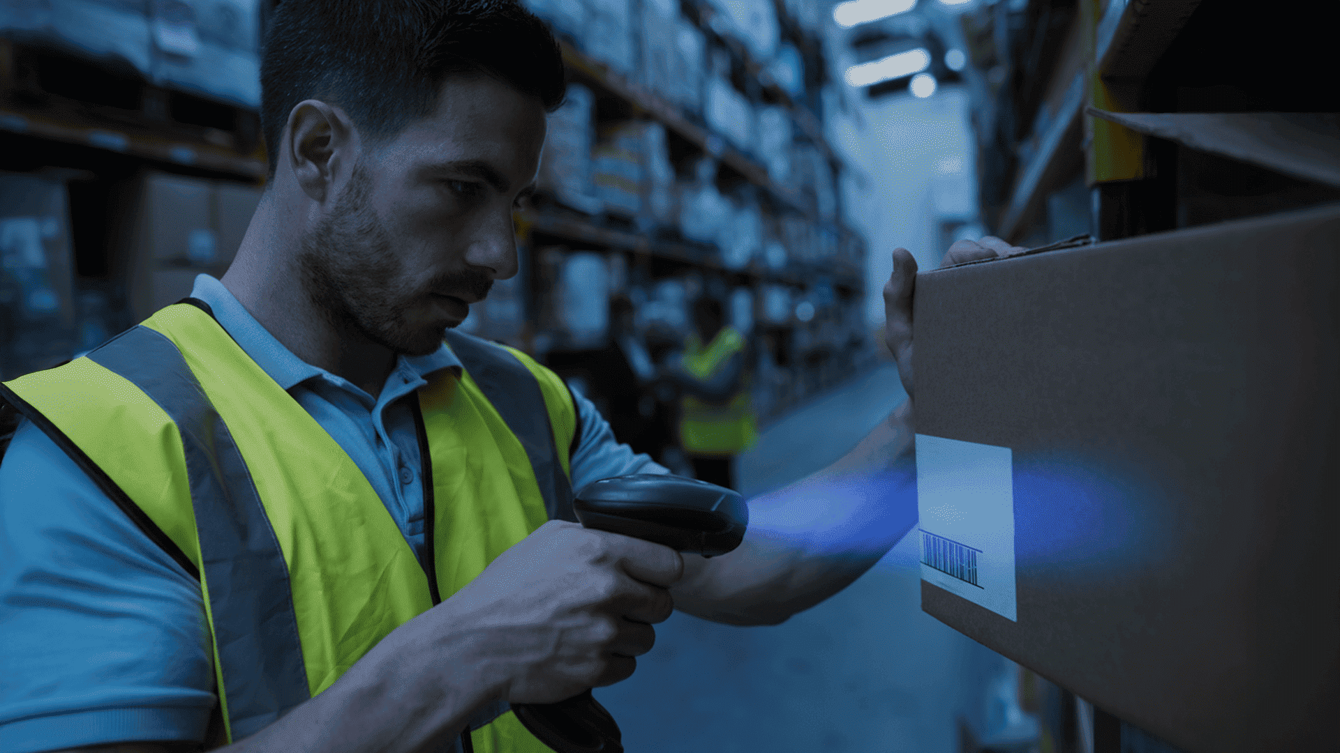 Warehouse worker scanning barcode on a box with a handheld scanner.