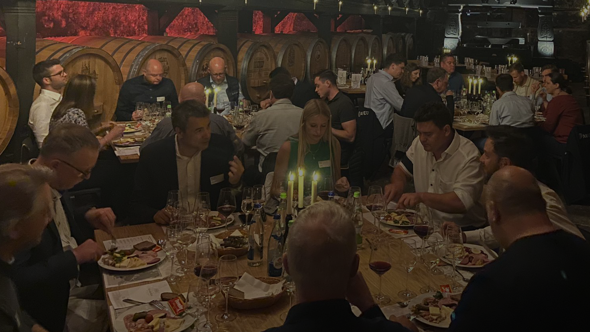 Personen bei einem festlichen Abendessen in einem Weinkeller.