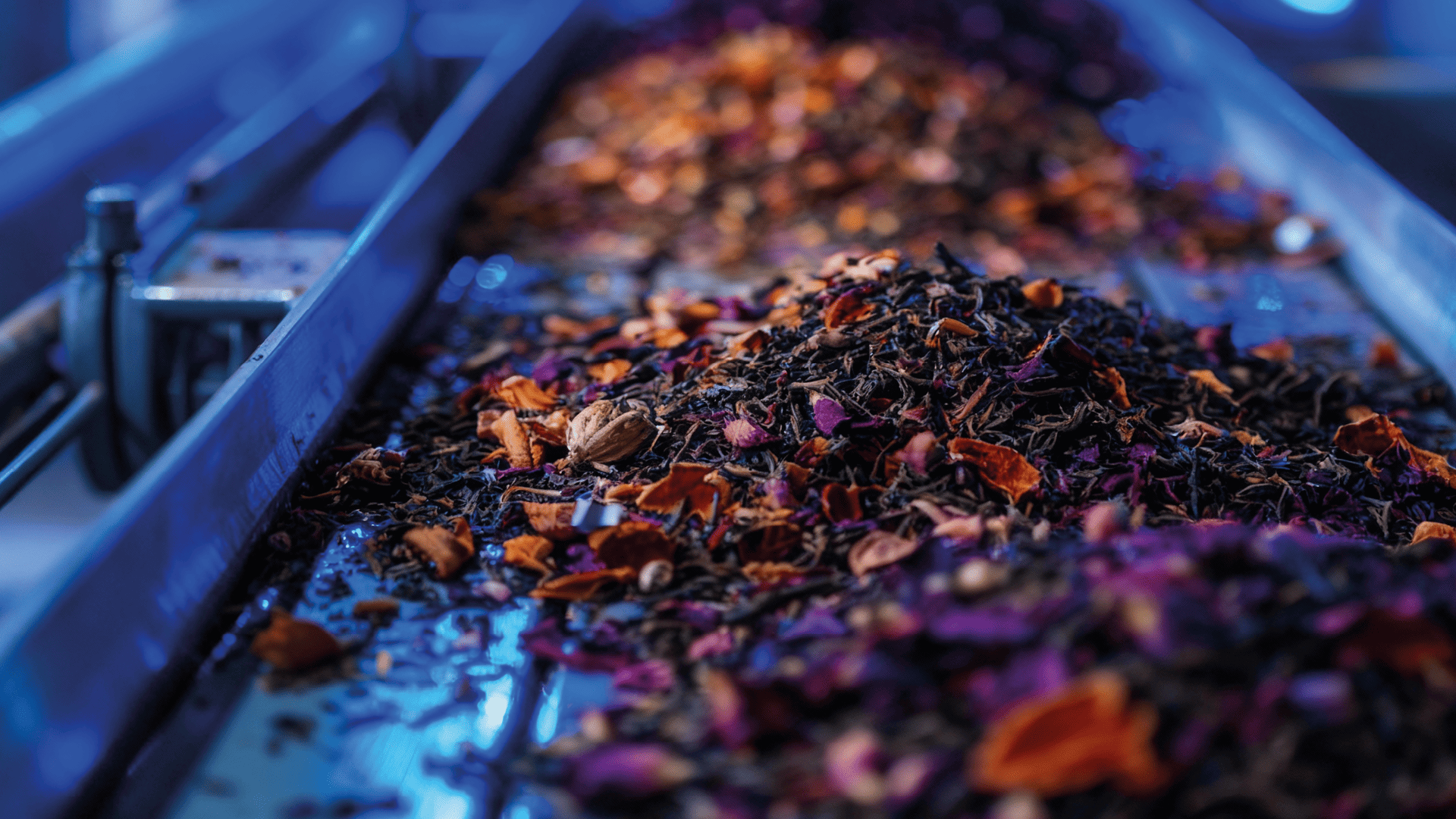 Machine sorts colorful tea blend with flowers and spices.