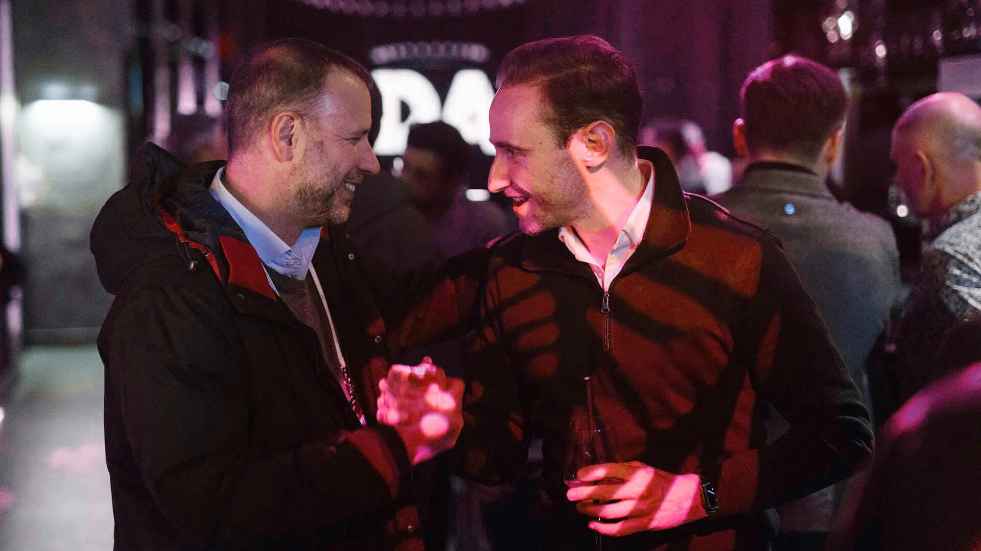 Zwei Männer unterhalten sich lächelnd bei einem Event.