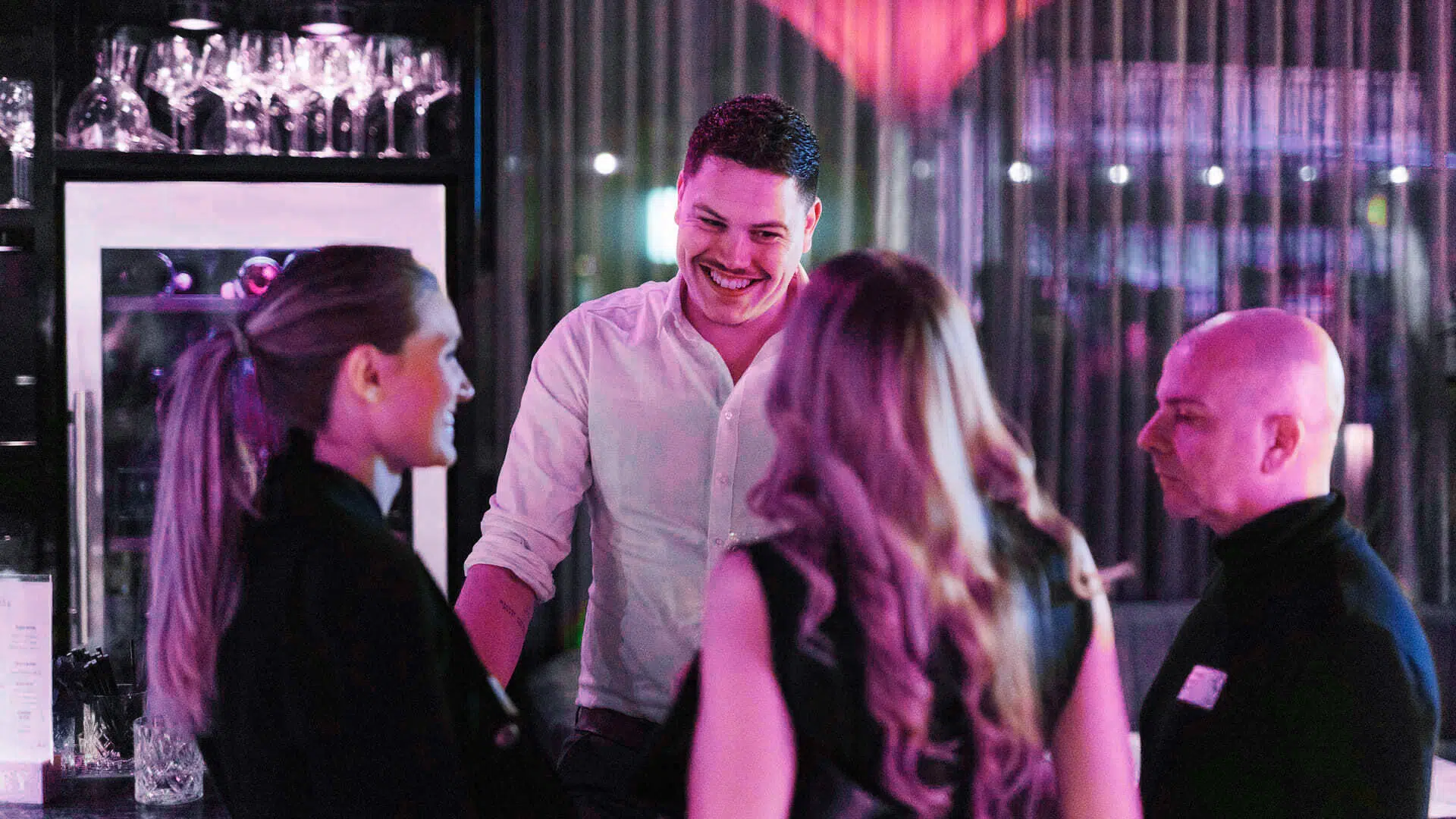 Gruppe von Menschen unterhalten sich in einer Bar bei Abendbeleuchtung.