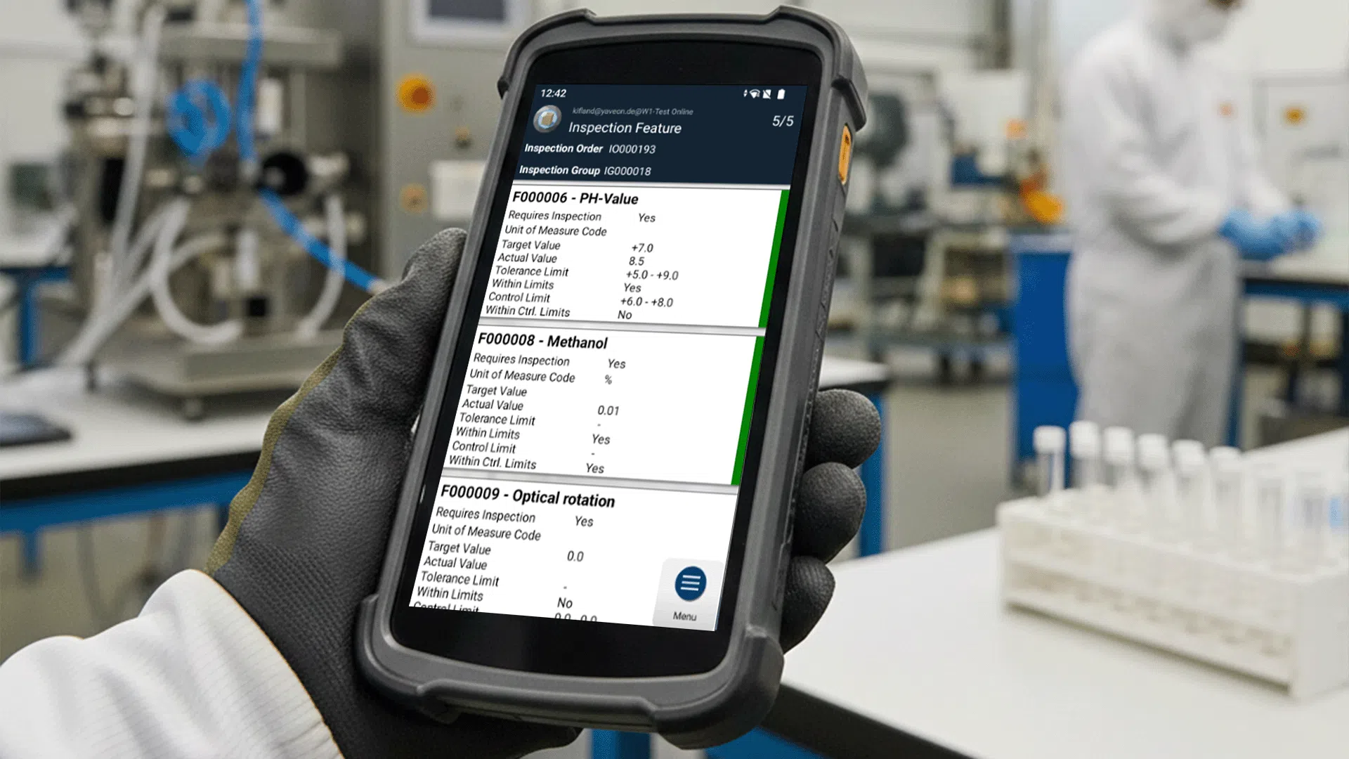 Person mit Handschuh hält Gerät mit Inspektionsdaten im Labor.
